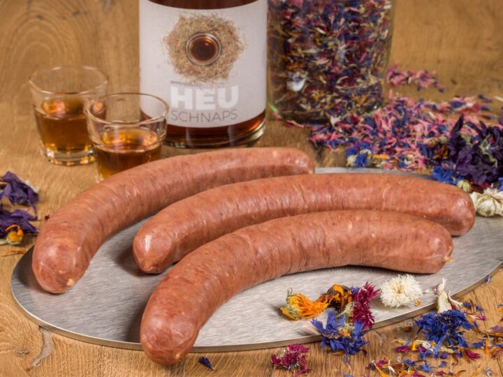 Die Juni-Extrawurst 2026: Heubluemeschüblig Jetzt startet nicht nur der Alpsommer zwischen Säntis und Churfirsten, sondern auch die Wandersaison. Die Bergwiesen werden bunt, es duftet nach Kräutern und frischem Gras. Da liegt es nahe, eine passende Extrawurst zu kreieren: den Heubluemeschüblig. Gemacht für einen bodenständigen Zmittag auf der Alp. Oder für Wandersleute mit Hunger und fürs Bräteln über offenem Feuer. Verfeinert mit Heuschnaps, Kräutern und Kornblumen – mehr braucht es nicht für eine gelungene Pause. Dazu ein knuspriges Bürli, vielleicht einen Apfelsaft. Oder noch passender: ein kühler Toggenburger Bergkräuter-Eistee.